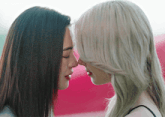 two women are touching their noses and looking at each other