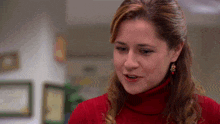 a woman wearing a red turtleneck sweater and earrings smiles