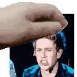 a hand is holding a man 's head in front of a picture of him .