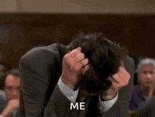 a man in a suit and tie is scratching his head while sitting in a courtroom .