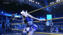 a woman is in a wrestling ring with the word wwe on the screen