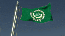 a green flag with arabic writing on it flies in the wind