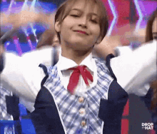 a girl in a blue and white plaid shirt with a red bow tie is dancing .