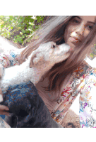 a woman in a floral shirt is holding a white dog and a black dog
