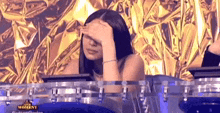 a woman is covering her face with her hand while sitting at a table .
