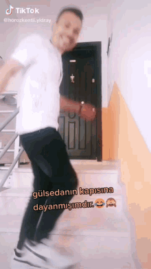 a man in a white shirt is dancing in front of a door that says tik tok