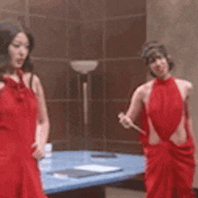 a woman in a red dress is standing in front of a mirror .