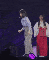 a woman in a blue shirt and white skirt is dancing on a stage