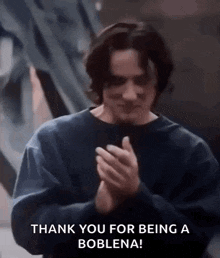 a man in a blue sweater is clapping his hands and saying `` thank you for being a boblena '' .