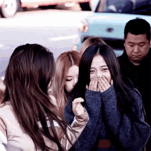 a woman covering her face with her hands while standing next to another woman