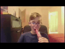 a boy wearing glasses is eating a popsicle