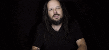 a man with long hair and a beard is smiling and making a face .
