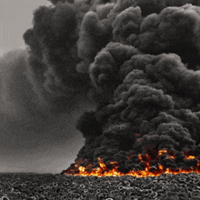 a pile of tires are burning in a field with smoke coming out of them