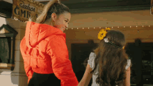 a woman in an orange jacket holds the hand of a little girl