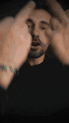 a man with a beard is making a hand gesture with his hands .