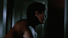 a man without a shirt is standing in a dark room