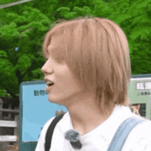 a close up of a person 's face with long blonde hair and a backpack .