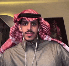 a man wearing a keffiyeh and earbuds looks at the camera