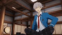a boy in a blue jacket and tie is sitting on the floor