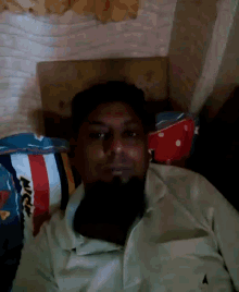 a man with a beard is laying on a bed with a striped pillow that says nice on it