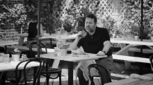 a man is sitting at a table eating a sandwich