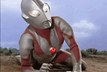 a superhero with a red button on his chest is kneeling on the ground