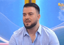 a man with a beard is smiling in front of a blue background
