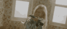 a woman is laughing while holding a camera in front of her face .