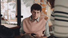 a man in a pink vest is looking at a cell phone