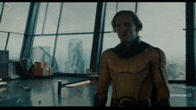a man in a yellow superhero costume is standing in front of a window