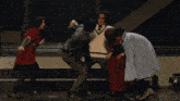 a group of people are dancing on a stage and one woman is wearing a blue cape