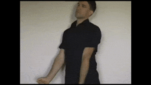 a man in a black shirt is standing in front of a wall
