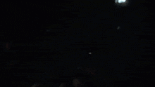 a group of people are sitting in a dark auditorium watching a movie .