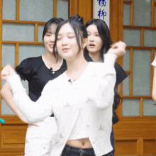 a woman in a white sweater is dancing in front of a wooden door with chinese writing on it