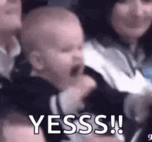 a baby is crying in a woman 's arms while a group of people laugh .