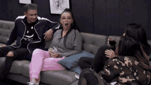 a group of people are sitting on a couch and one of them is wearing a jacket that says hey but i love you