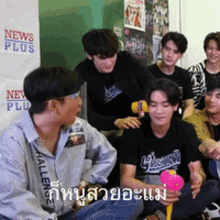 a group of men are sitting in front of a news plus sign