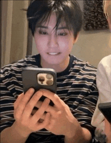 a man in a striped shirt is holding a cell phone .
