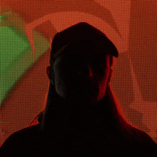 a silhouette of a woman wearing a black hat in front of a red and green background