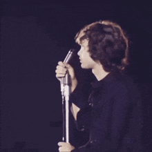 a man is singing into a microphone in a dark room