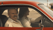 a man and a woman are sitting in a red car with max written on the bottom