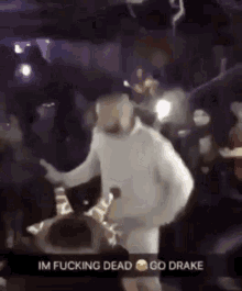 a man in a white sweater is dancing in front of a crowd in a club .