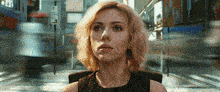 a woman in a black dress is sitting in front of a blurry street