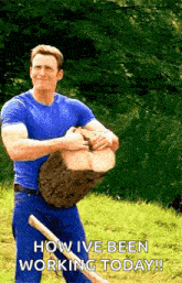 a man in a blue shirt is holding a large log with a shovel .