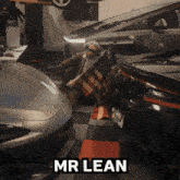 a man is holding an american flag in a garage with the name mr lean written above him