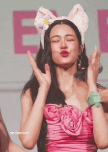 a woman in a pink dress is wearing a cat ear headband and making a face .