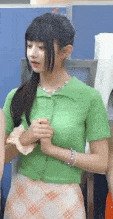 a girl wearing a green shirt and a plaid skirt is standing next to another girl .