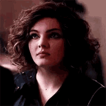 a close up of a woman 's face with curly hair .