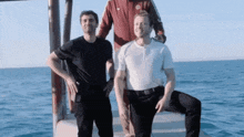 three men are posing for a picture while standing on a boat in the ocean