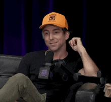 a man wearing an orange hat with the word aaron on it sits in front of a microphone